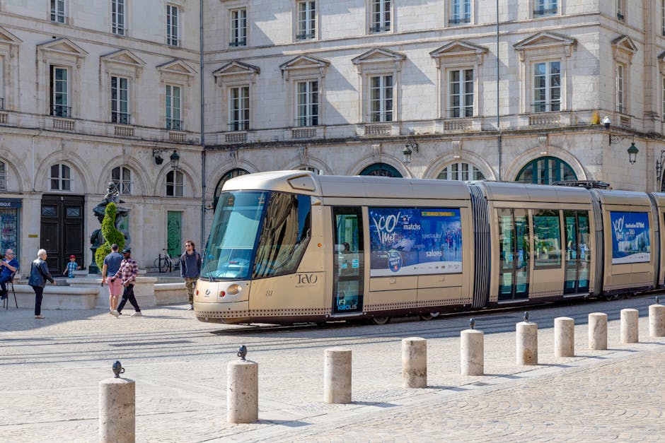 A modern tram travels through a historic square in Orléans, France under a sunny blue sky.