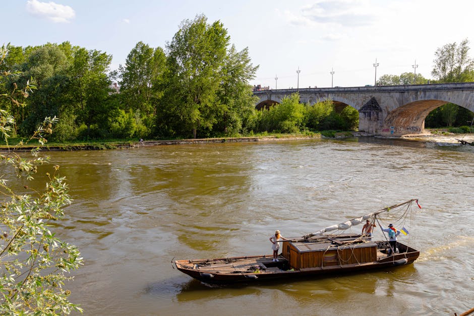 A traditional wooden boat sails along the Loire River under a historic stone bridge